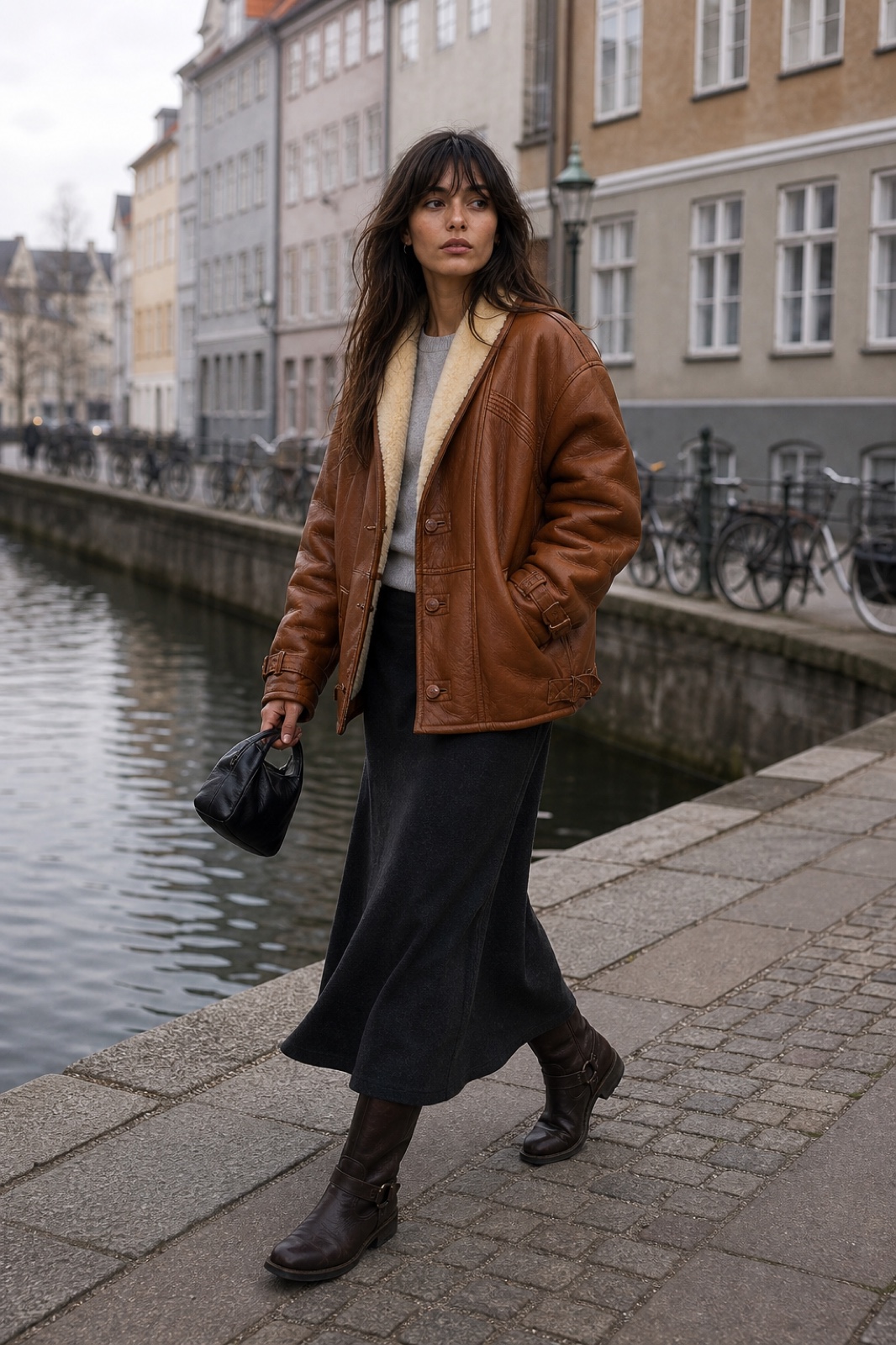 Ines wearing a short cognac shearling coat with a high-waisted skirt.